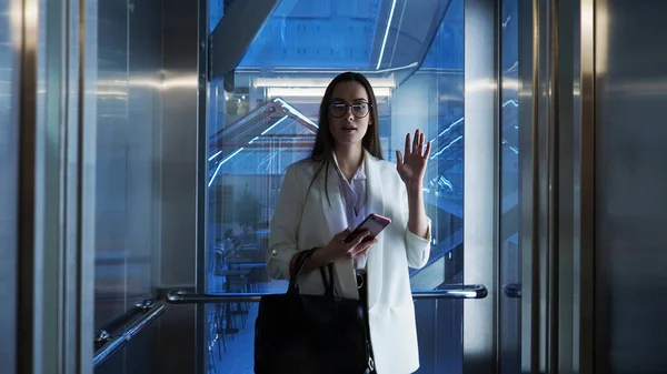 İş merkezindeki asansördeki genç iş kadını, iş arkadaşlarının gayri resmi selamı.. — Stok fotoğraf
