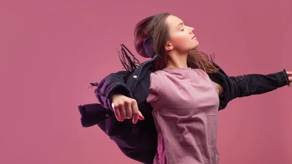 Весела дівчина в облямованій куртці танцює на рожевому фоні . — стокове фото