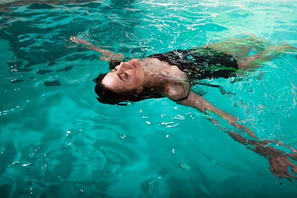 Güzel kız Spa havuzunda dinleniyor, yüzüyor ve rahatlıyor. Yüzen genç kadın — Stok fotoğraf
