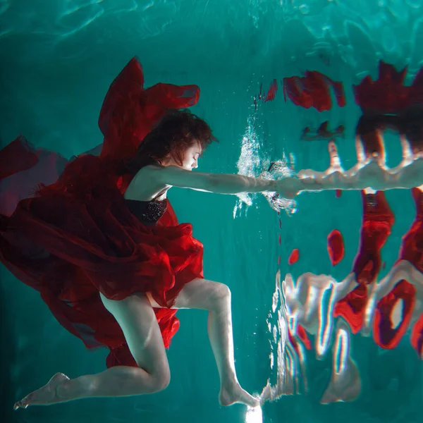 Mystical underwater portrait of a beautiful young woman in a red dress. — Stock Photo, Image