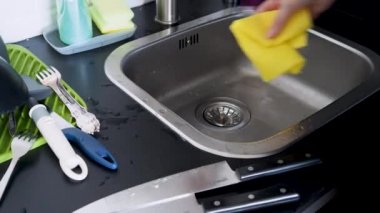 Elle bulaşık yıkayan, eldivensiz genç bir kadın bıçakları yıkıyor.