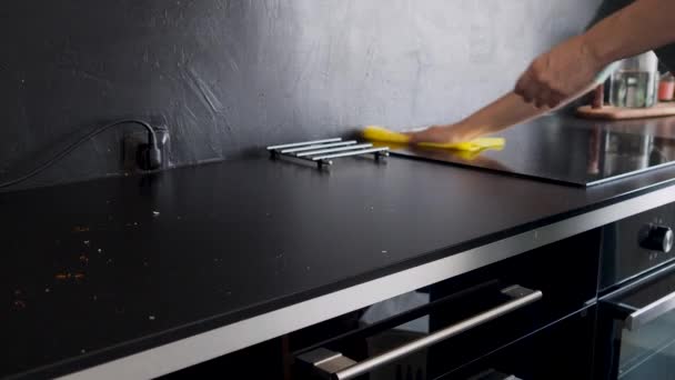 Hausarbeit, Reinigung der Küche. Schwarze Arbeitsplatte und Kochfläche von Krümeln befreien, — Stockvideo