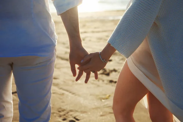 Amore, romanticismo sulla spiaggia. Giovane bella coppia, donna, uomo, in bianco sciolti abiti volanti, a piedi, lungo la riva del mare . — Foto Stock