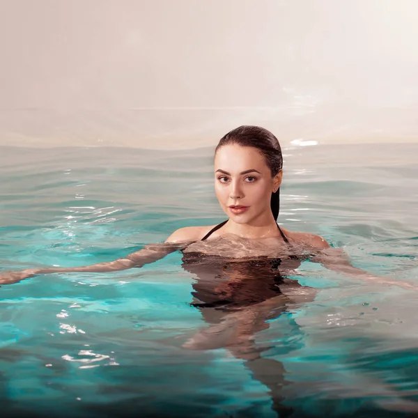 Belle jeune femme nageant dans la piscine, portrait. Jolie fille brune — Photo