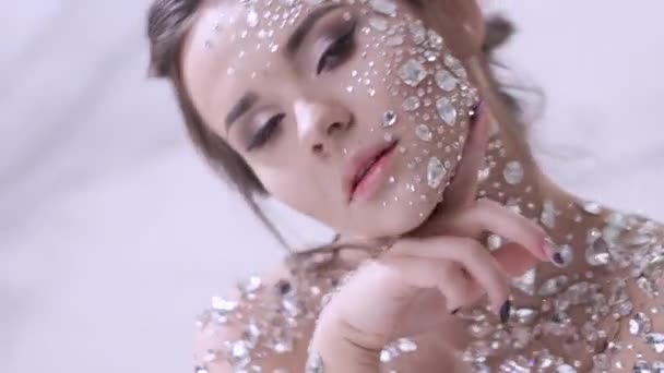 Ongebruikelijke make-up en gezicht kunst met sprankelende strass op de huid. — Stockvideo