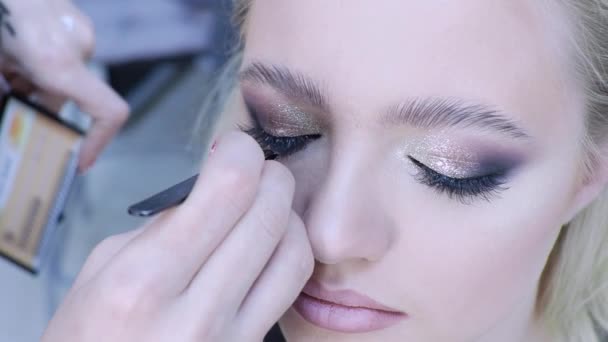 Eyelash extensions, make-up master lijmt trossen wimpers, een helder glamoureus beeld voor een feestje. — Stockvideo