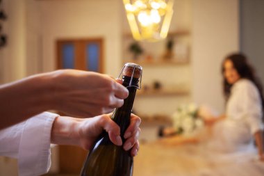 Şampanyayı aç. Ön planda bir kadın eli,