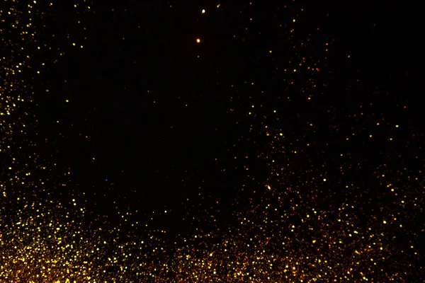 Abstrakter Urlaubshintergrund, goldener Stardust auf Schwarz. — Stockfoto