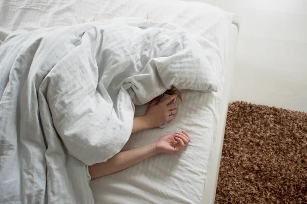 Morning, the woman under the blanket, turns off the alarm clock — Stock Photo, Image