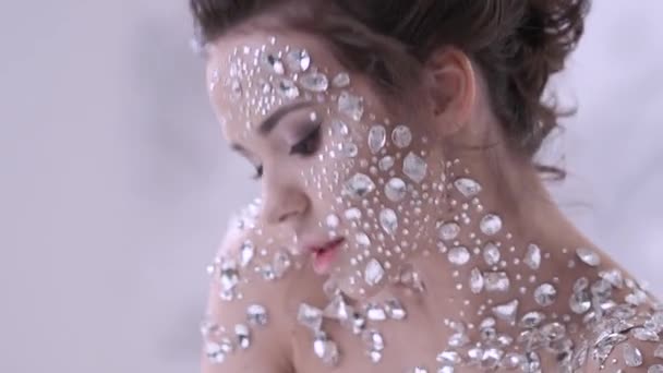 Maquillaje inusual y arte de la cara con diamantes de imitación brillantes en la piel . — Vídeos de Stock