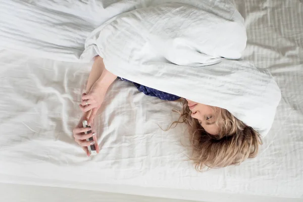 Morgon, kvinnan under filten, stänger av väckarklockan. — Stockfoto