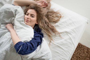 Mavi pijamalı, battaniyenin altında tatlı bir sarışın.