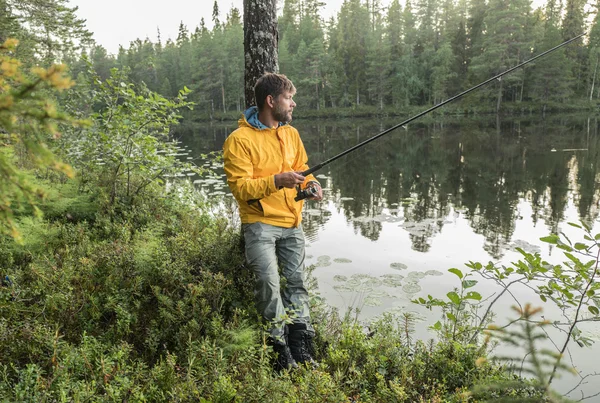 Man is de visserij op de oever van lake mooie bos — Stockfoto