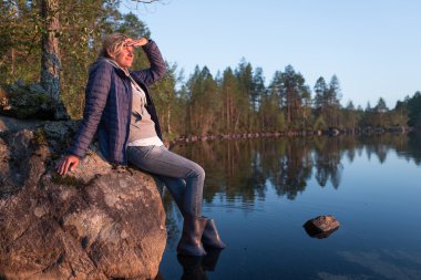 Güzel turist kadın arıyorum ve gün batımı göl yakınındaki taş inti üzerinde oturan mesafe