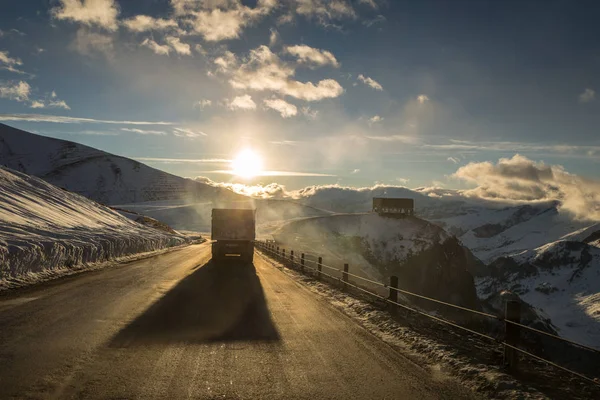 Vrachtwagen op de Georgische militaire weg op zonsondergang, winter Stockfoto