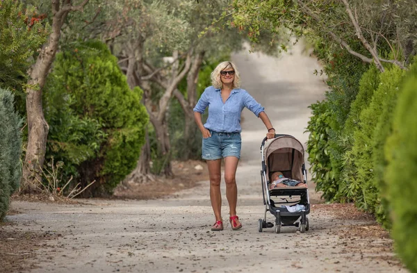 Kameraya gülümseyen bebek arabası ile genç anne