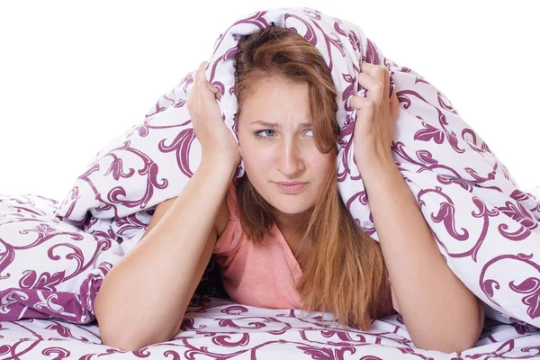 Bella giovane donna che soffre di insonnia e si copre la testa con un cuscino . — Foto Stock