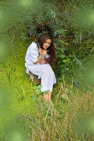 Связанная женщина у озера прячется за ветками — стоковое фото