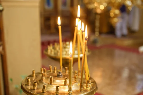 Burning candle in the church in front of the icons — Stock Photo, Image