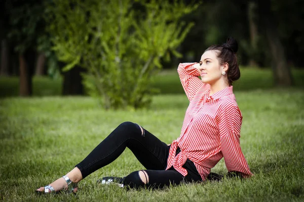 Beautiful girl sits on lawn — Stock Photo, Image