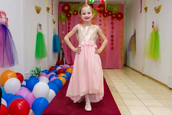 Счастливая красивая маленькая девочка показывает платье и весело проводит время — стоковое фото