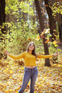 Park açık havada yürüyüş için sonbahar yaprakları kadar mutlu kız atıyor.