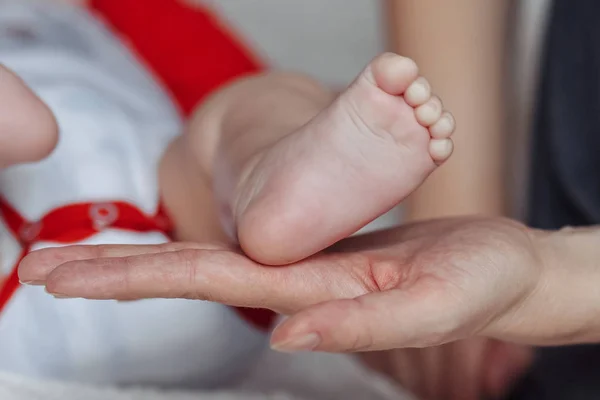 Anne bebek ayaklarını elinde tutuyor.. — Stok fotoğraf