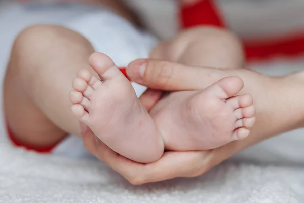 Anne bebek ayaklarını elinde tutuyor.. — Stok fotoğraf