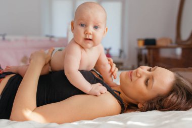 Anne, küçük oğluyla yatakta oynuyor..