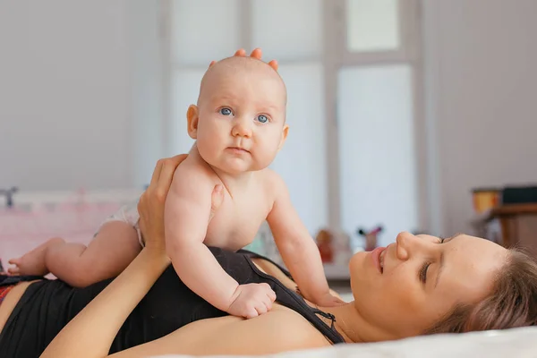 Madre giocare con il suo bambino ragazzo figlio su letto . — Foto Stock