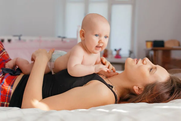 Mutter spielt mit ihrem kleinen Sohn auf dem Bett. — Stockfoto