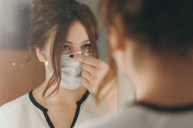 Açık renk saçlı kadın virüse karşı korunmak için tıbbi maske takıyor.