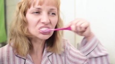 Banyoda dişlerini fırçalayan kadın.