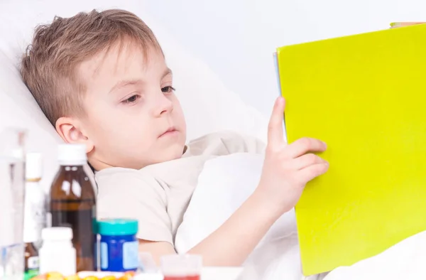 Chory chłopiec w łóżku czytając książki — Zdjęcie stockowe
