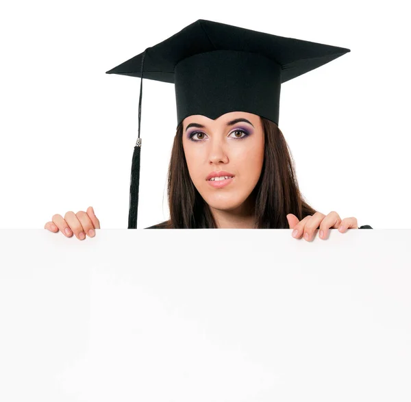 白い背景に隔離された空白のパネルの後ろから覗く女子学生 空白のプラカードボードを示すマントルで美しい大学院の十代の女子学生 — ストック写真