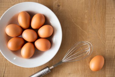 Tahta arka planda tavuk yumurtası ve yumurta çırpıcısı..