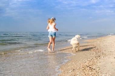 onun golden retriever ile plaj kıyısında sabahın erken sırasında çalışan genç kız.