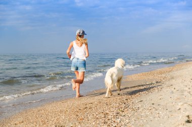 onun golden retriever ile plaj kıyısında sabahın erken sırasında çalışan genç kız.