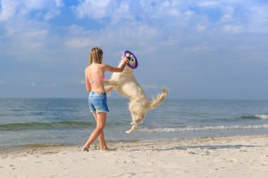 mutlu kız sahilde bir köpekle oynamayı