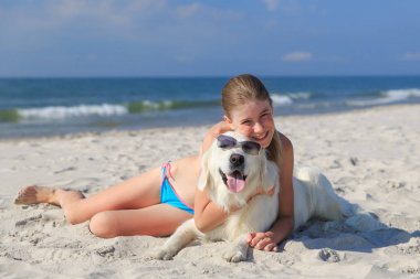 mutlu kız sahilde bir köpekle oynamayı