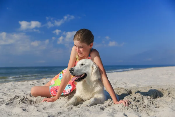 Menina feliz brincando com um cão na praia — Fotografia de Stock