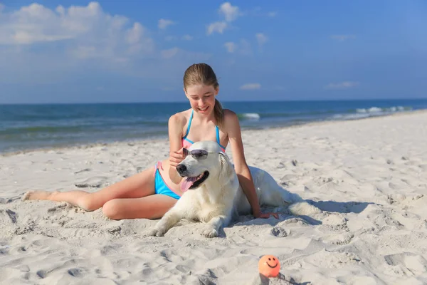 Mutlu kız sahilde bir köpekle oynamayı — Stok fotoğraf