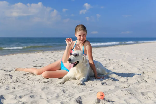 Mutlu kız sahilde bir köpekle oynamayı — Stok fotoğraf