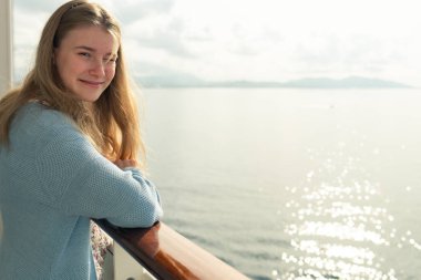 Gemi seyahati. Lüks yolcu gemisinin balkonunda dinlenen genç kız. Güneş doğarken bir yolcu gemisinde mutlu güzel bir kızın portresi.