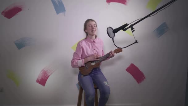 快乐的少女在家里用话筒唱歌和弹奏口琴 作为网络影响者的年轻女孩 为互联网录制Vlog和音乐教学 — 图库视频影像