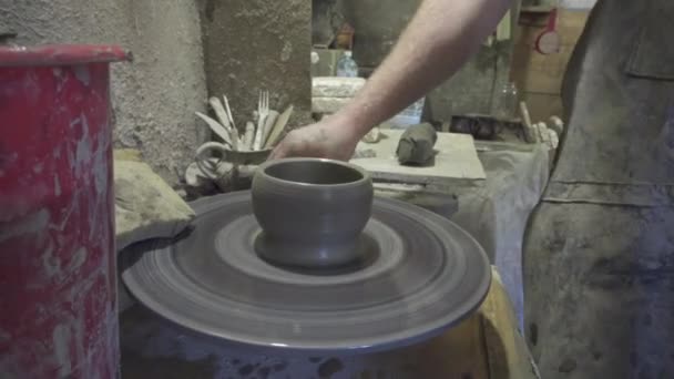 Potter shapes the clay product with pottery tools on the potters wheel, craft factory authentic — Stock Video