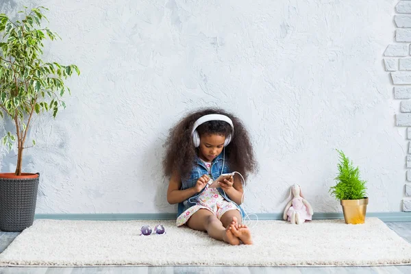 Linda chica afro en casa escuchando música — Foto de Stock