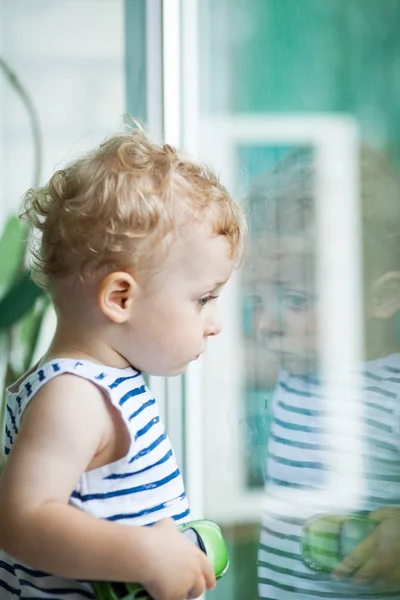 Kleine jongen de regen door het raam kijken — Stockfoto