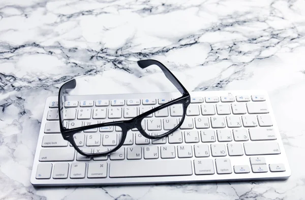 Gafas para los ojos en un escritorio o escena de oficina con teclado — Foto de Stock