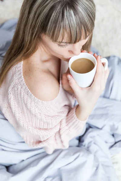 Beauty Portrait Relaxed Woman in the Morning and Drinks Coffee in Bed. Caucasian young woman Relaxed in Bed with cup of coffee
